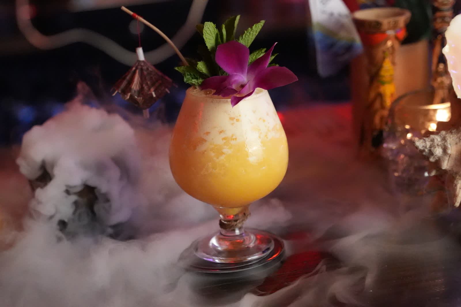 Tropical cocktail with dry ice smoke, orchid garnish and paper umbrella at Kaona Room Miami