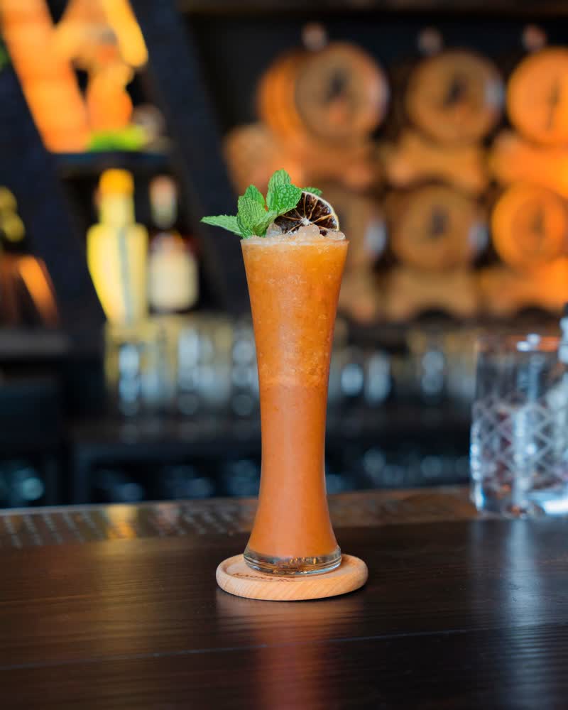Frozen tropical rum cocktail with mint and dried citrus garnish at Kaona Room bar