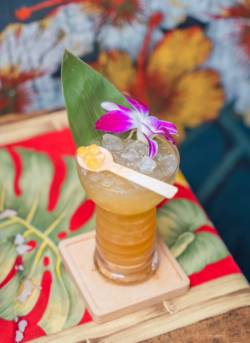 Tropical tiki cocktail with orchid, banana leaf garnish, and crushed ice at Kaona Room